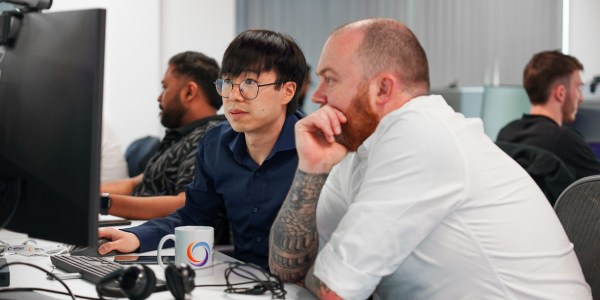 two men sat discussing a computer screen