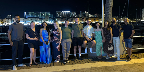 A group of people stood in a line smiling Infront of a marina
