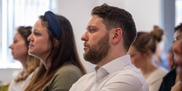 A man and woman sat listening from a side angle