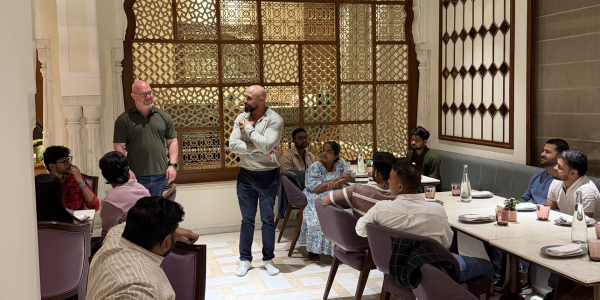 Two people standing up and talking infront of a team