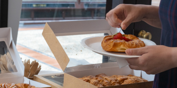 a person grabbing some pastries onto a plate