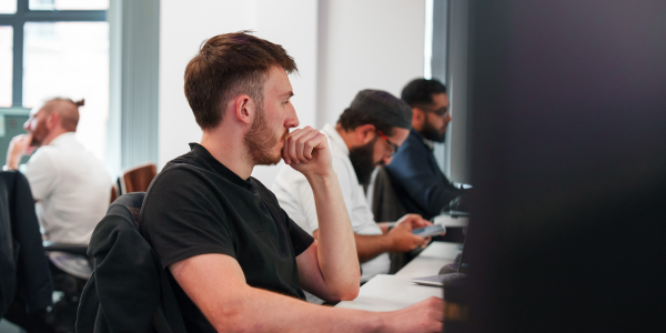 man sat with hand to chin thinking whilst looking at a screen.