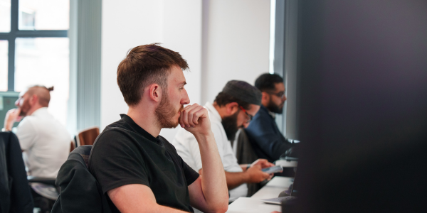 A man looking at a computer intently whilst having his hand to his chin