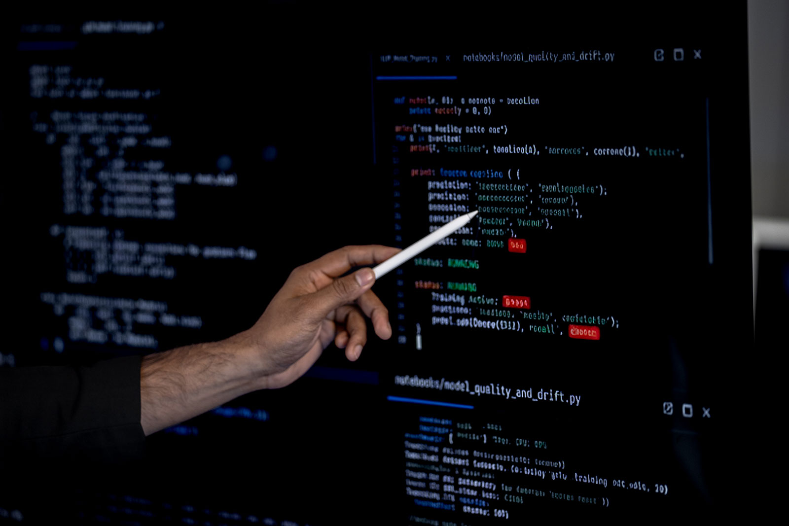 Hand pointing a stylus at Python code on a screen, in a file for monitoring machine learning model quality and drift