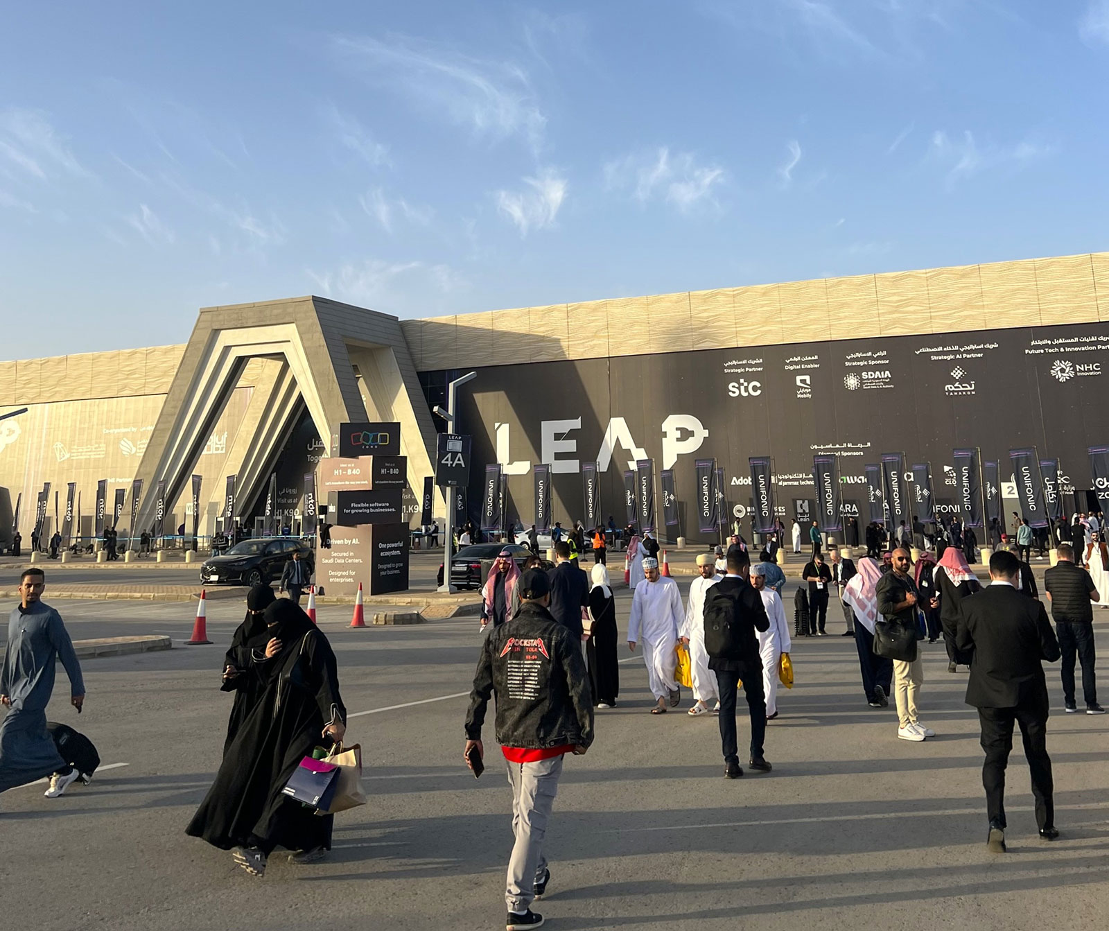 Crowds of visitors walking towards the entrance of the LEAP technology conference venue in Riyadh on a sunny day