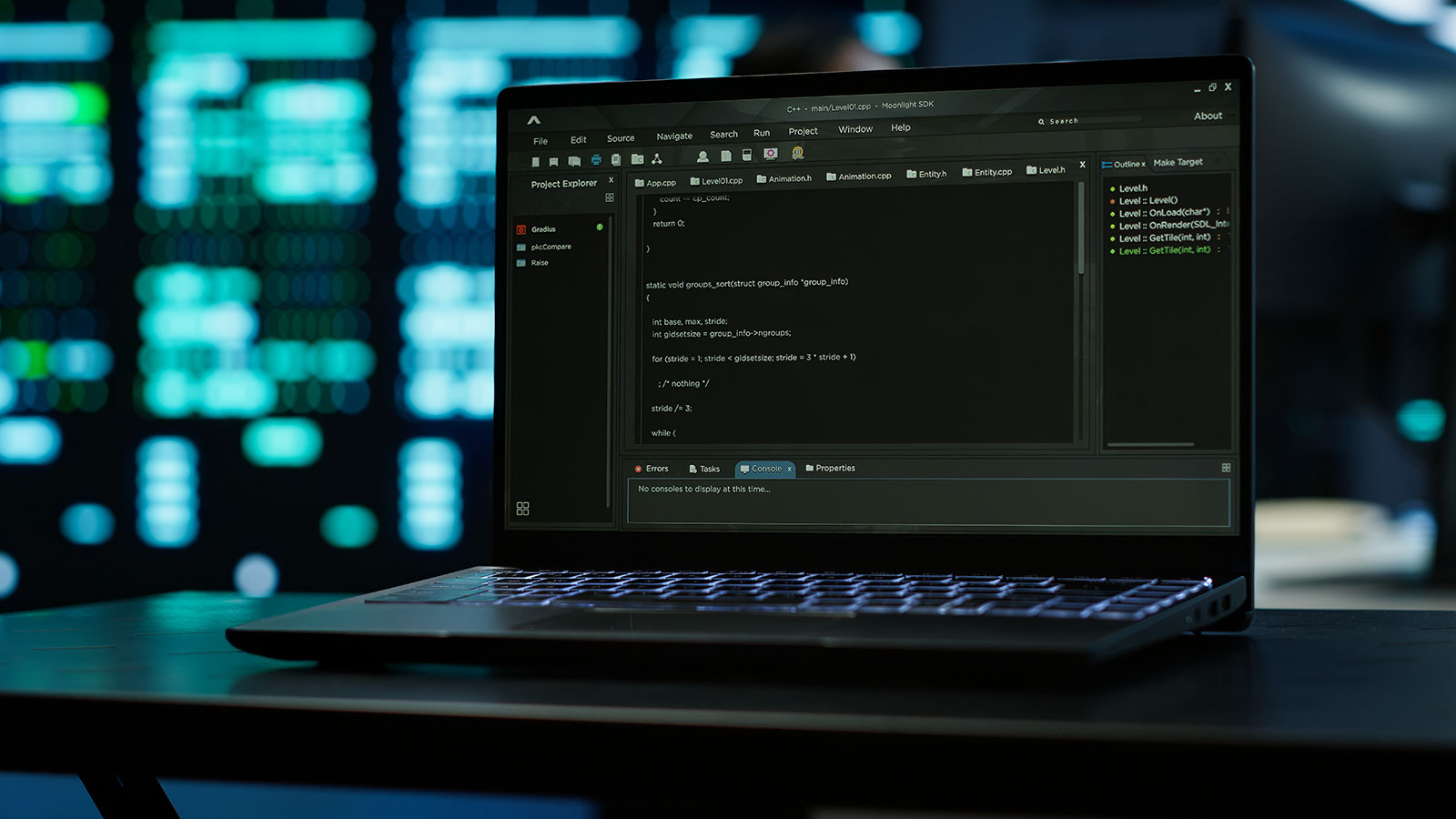 Laptop on a desk displaying C++ code in a development environment, with blurred server racks glowing in the background