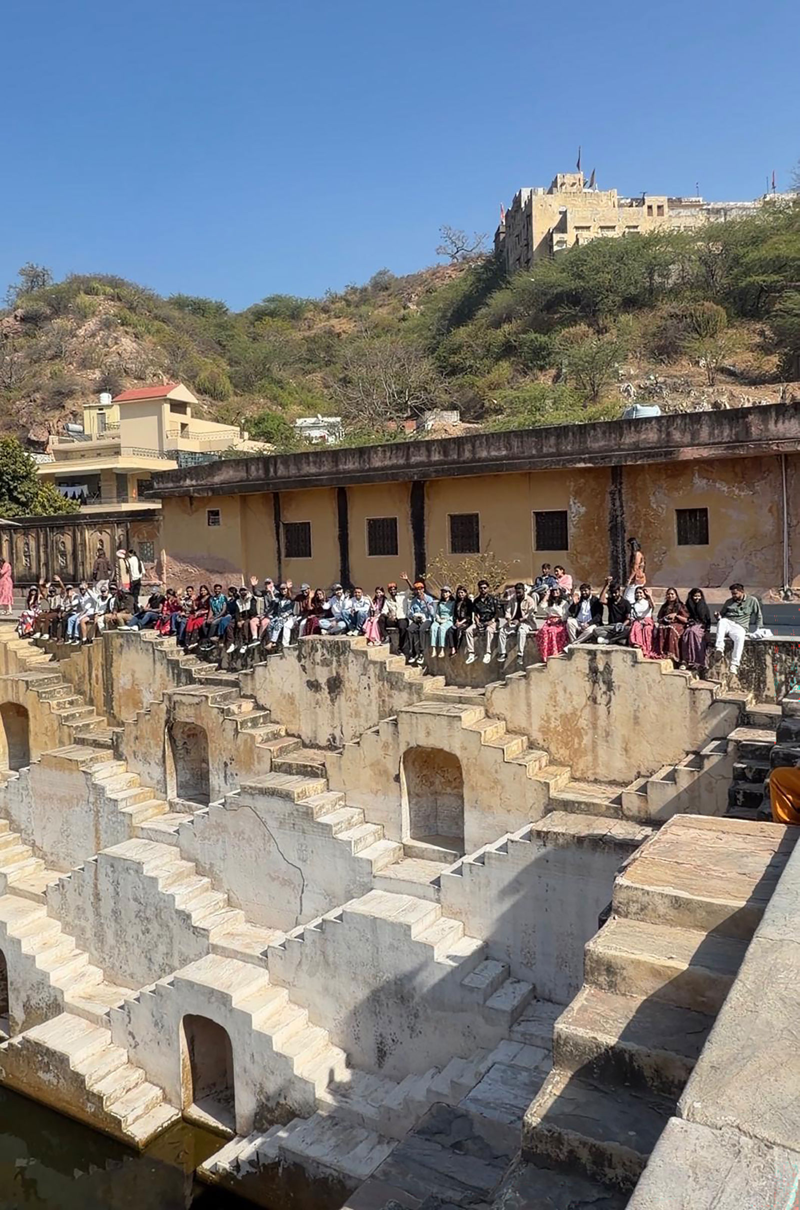 ur India team seated along the top of the Panna Meena ka Kund stepwell on our annual team-building trip, beneath a sunny hillside